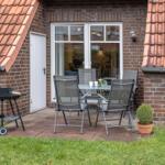 Terrasse mit Tisch, Stühlen, Grill und Pflanze vor Backsteinhaus