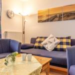 Wohnzimmer mit Sofa, Sesseln, Tisch und Wandbildern