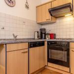 Küche mit Holzschränken, Spüle, Herd und Mikrowelle