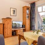 Wohnzimmer mit Holzmöbeln, Fernseher und Blick auf die Terrasse.