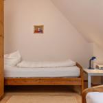 Ein Schlafzimmer mit Holzbett, Kleiderschrank und Nachttisch unter Dachschrägen.