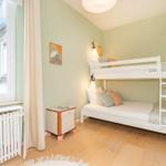 Zimmer mit Doppelstockbett, Fenster und Holzboden. Wandfarbe mintgrün.