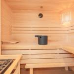 Sauna mit Holzbänken, Thermometer und schwarzer Schale.
