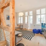Wohnraum mit Holzrahmen, Sofa, TV und blauen Sitzkissen.