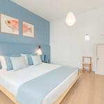 Schlafzimmer mit Bett, Wandbildern und Holzboden.