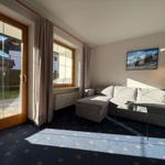 Wohnzimmer mit Sofa, Glas-Tisch und Blick auf den Garten.