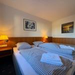 Zimmer mit Doppelbett, zwei Nachttischen und Wandbildern.