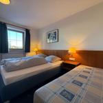 Zwei Betten mit Bettwäsche, Nachttische und Lampen. Fenster mit Vorhängen und Wandbild.