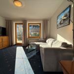 Wohnzimmer mit Sofa, Fernseher und Fenster zur Terrasse.