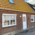 Rotes Ziegeldach mit Dachfenster, weiße Tür und Fenster an rotem Backsteinhaus mit Hausnummer 79.