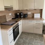 Küche mit hellen Schränken, Holzoberflächen und gemustertem Bodenbelag.