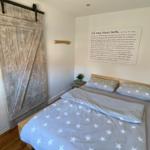 Schlafzimmer mit Bett, Holztür und Wandtext.