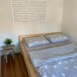 Ein Bett mit Sternenbezug, Holzrahmen und Wandtext über Ostsee.