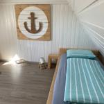 Ein Bett mit gestreifter Bettwäsche, Wanddekoration mit Anker und Holzmöbel.