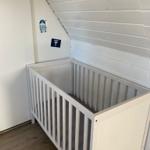 Kinderbett in einem Raum mit schräger Decke und Holzfußboden.