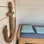 Hölzernes Bett mit Kissen und Wanddekoration in Form eines Ankers.