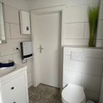 Badezimmer mit Toilette, Waschbecken und bodenfliesen.