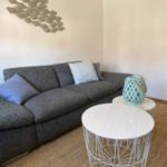 Ein grauer Sofa mit Kissen, zwei runde Tische und Wanddekoration mit Fischen.