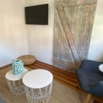 Raum mit Holztür, TV, zwei runden Tischen und Sitzgelegenheit.