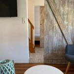 Wohnbereich mit Holztür, Fernseher und Tisch. Treppenhaus führt zur Schlafstube.