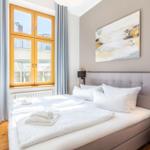 Schlafzimmer mit Doppelbett, Wandbild und Fenster mit Holzrahmen.