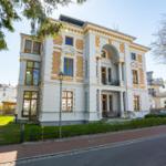 Elegantes Haus mit goldfarbenen Verzierungen und großzügigem Vorgarten.