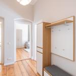 Flur mit Holzboden, Kleiderschrank und Blick in Küche und Wohnzimmer.