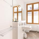 Badezimmer mit Waschbecken, Spiegel, Dusche und Fenster mit Holzrahmen.