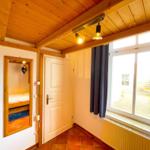 Raum mit Holzdecke, Fenster, Tür und Blick in Schlafzimmer.