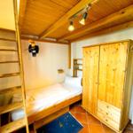 Ein Schlafzimmer mit Holzbett, Kleiderschrank und Decke. An der Wand hängt ein Vogel.
