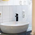 Waschbecken mit schwarzem Wasserhahn auf grauer Arbeitsplatte