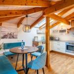 Essbereich mit runder Tisch und blauen Stühlen unter Holzbalkendecke