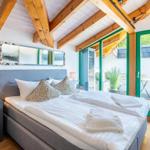 Schlafzimmer mit Doppelbett, Holzbalkendecke und Glasfront zur Terrasse.