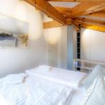 Schlafzimmer mit Doppelbett, Holzbalkendecke und Wandbild mit Strandmotiv.