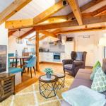 Wohnbereich mit Sofa, Couchtisch und Fernseher unter Holzbalkendecke