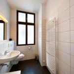 Badezimmer mit Waschbecken, Toilette, Heizung und Fenster.