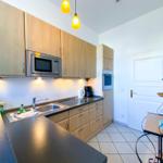 Küche mit Holzschränken, Mikrowelle, Kühlschrank und Arbeitsplatte.