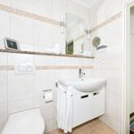 Badezimmer mit Waschbecken, Spiegel, Toilette und Handtuchhalter.