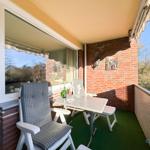 Terrasse mit Tisch, Stühlen und grünem Boden. Roter Ziegelwand und Sonnenschutz.