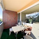 Terrasse mit Tisch, Stühlen und grünem Bodenbelag. Roter Ziegelwand und Glasfront.