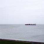 Vom Fenster aus Blick auf das Meer mit einem Containerschiff in der Ferne.