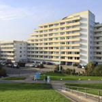 Hochhaus mit Balkonen und Parkplatz vor grünem Rasen