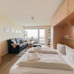 Zimmer mit Schlafplatz, Sofa, Tisch und Balkon mit Meerblick.