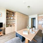 Wohnküche mit Esstisch, TV und Holzmöbel. Küche mit Mikrowelle und Spüle.