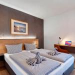 Doppelbett mit Schwänen aus Handtüchern, Schreibtisch und Blick auf Balkon.