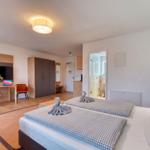 Zimmer mit Doppelbett, Schreibtisch, Kleiderschrank und Bad. Handtücher als Schwäne dekoriert.