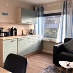 Küche mit Arbeitsfläche, Spüle und Küchenzeile. Wohnbereich mit Sofa und Fenster.