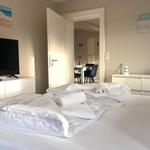 Schlafzimmer mit Bett, Fernseher und Blick in Esszimmer