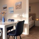 Essbereich mit Tisch und Stühlen, Schlafzimmer mit Bett und Nachttisch sichtbar.