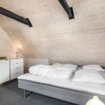 Bedroom with sloped ceiling, bed, dresser, and wood walls